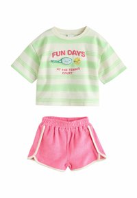 T-shirt a maniche corte verde e bianco a righe con grafica di tennis e testo rosa, abbinato a pantaloni corti rosa con rifiniture bianche e vita elastica.