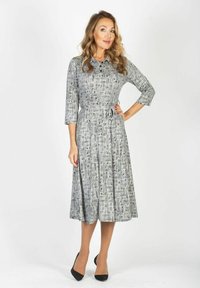 Sukienka z długim rękawem, zapinana na guziki, w abstrakcyjny czarno-biały wzór, z paskiem w komplecie wcięta w talii, z rozkloszowanym dołem, długość do kolan.