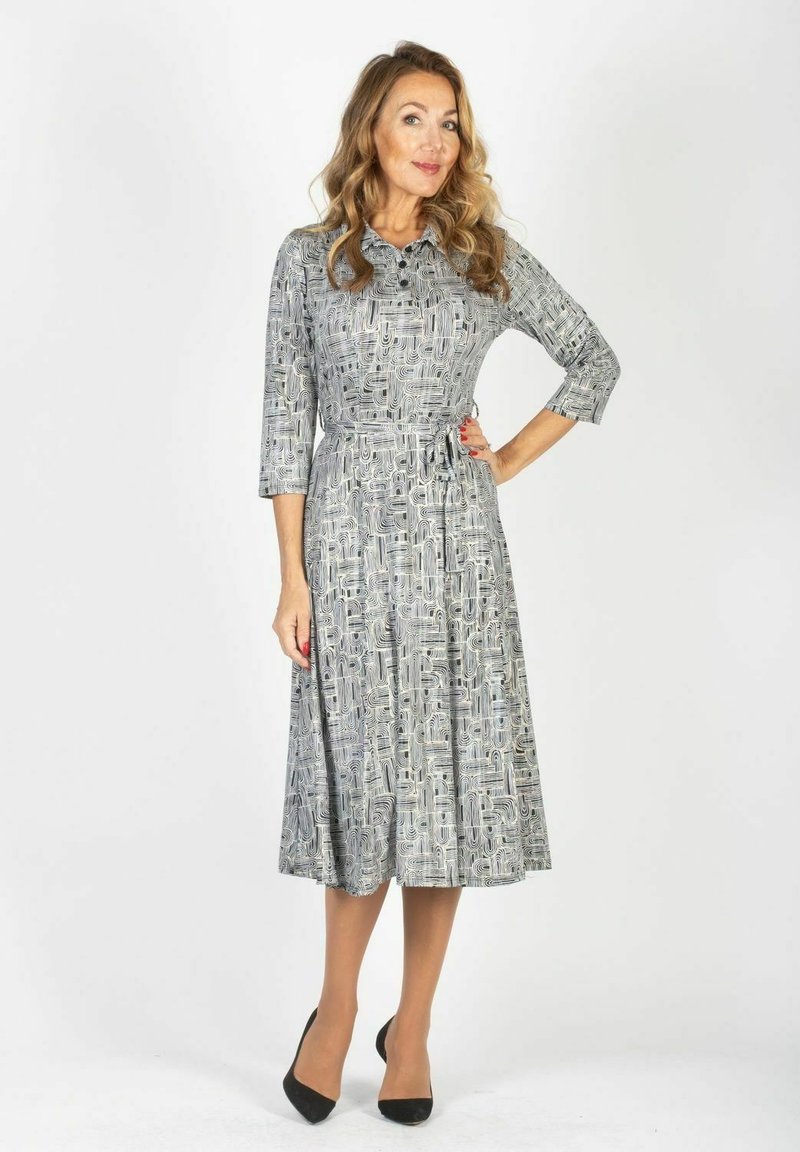 Sukienka z długim rękawem, zapinana na guziki, w abstrakcyjny czarno-biały wzór, z paskiem w komplecie wcięta w talii, z rozkloszowanym dołem, długość do kolan.