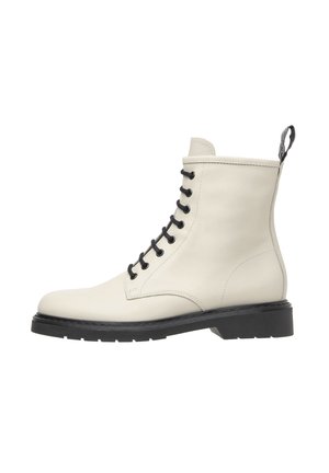 Hvide læder ankelstøvler med sorte snørebånd, rund tå og en struktureret sort gummisål. Har en løkke bagpå for nem påtagning.