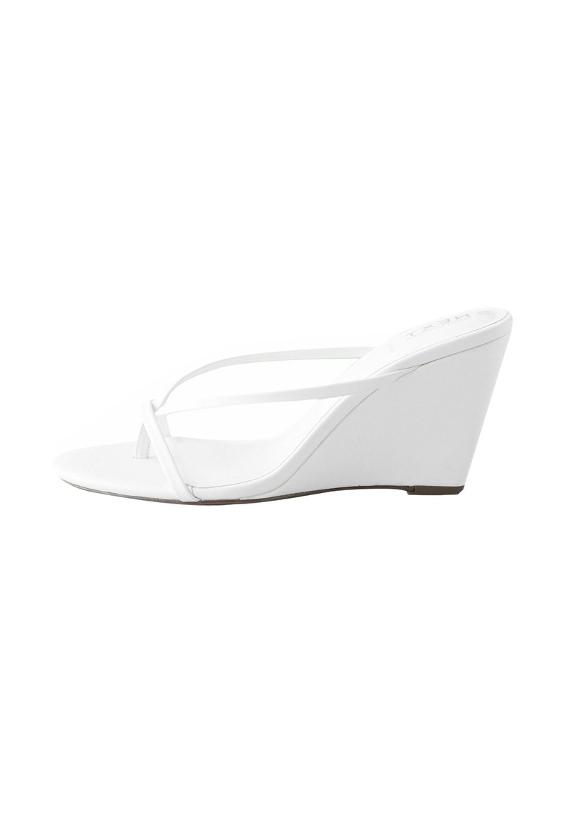 Sandales compensées blanches au design épuré, avec une texture lisse et des fines lanières. Le talon compensé offre une montée progressive depuis la semelle.