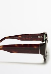 Srnkové sluneční brýle s širokými rámy, s hladkým povrchem, stříbrnými kovovými prvky pro panty a vygravírovanými detaily UV ochrany.