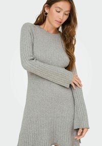 Robe pull grise à côtes avec manches longues et col rond. Présente une coupe ample et un ourlet brut pour un look décontracté.