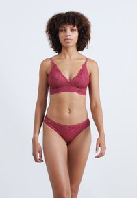 Set di reggiseno in pizzo bordeaux e bikini con motivi floreali, spalline regolabili e texture morbida. Adatto per un comfort quotidiano.