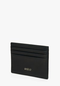 Zwarte leren kaarthouder met vier kaartsleuven en een debossed logo aan de voorkant. Gladde textuur met nette stiksels langs de randen.