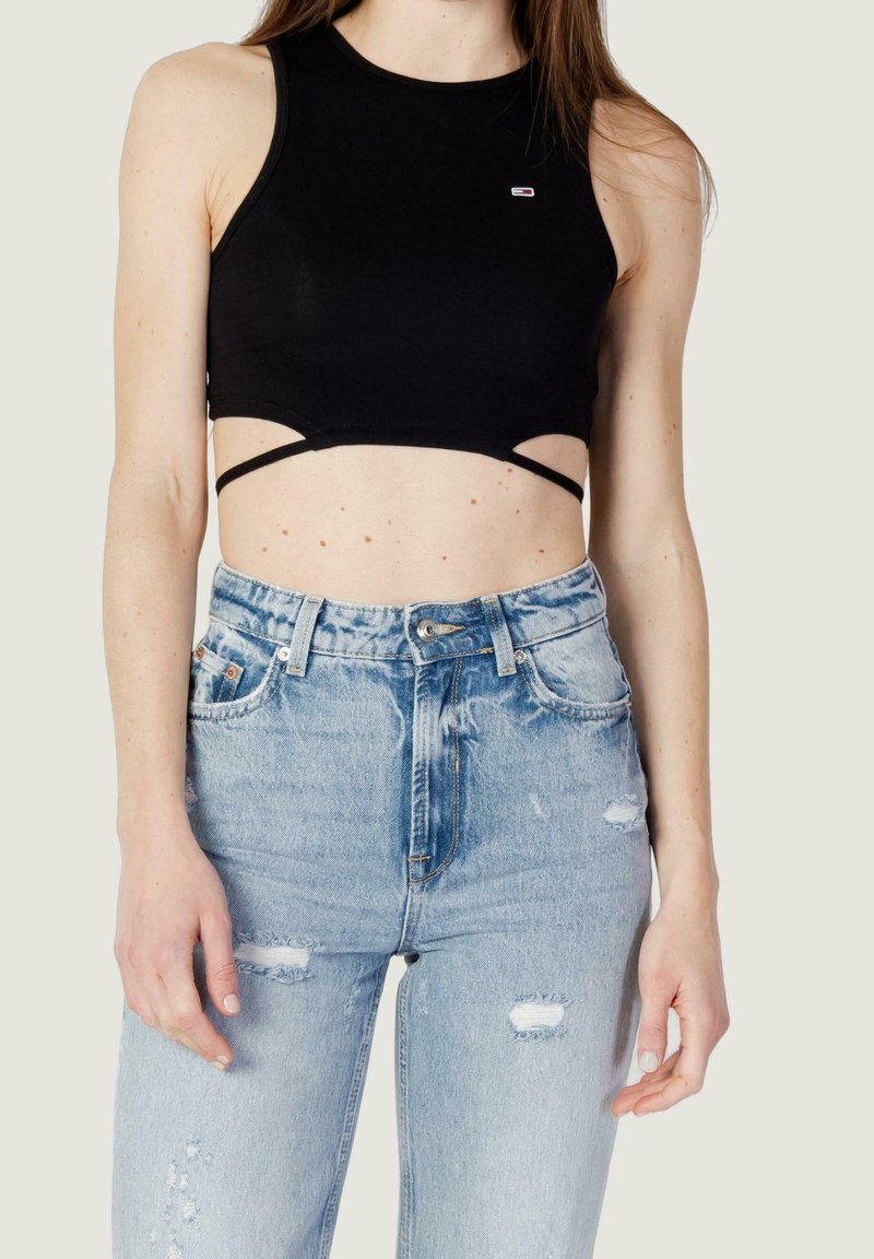 Haut court noir sans manches avec détails découpés et fines bretelles, assorti à un jean taille haute bleu clair déchiré.