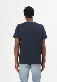 Navy blue cotton t-shirt with short sleeves, crew neck, and a relaxed fit. Notable detail includes a small logo on the left sleeve.