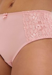 Rosa Unterwäsche mit einem glatten Stoffkörper und einem Spitzen-Seiteneinsatz, der mit Blumenmustern versehen ist. Abgerundet mit einem kleinen Schleifendetail an der Taille.