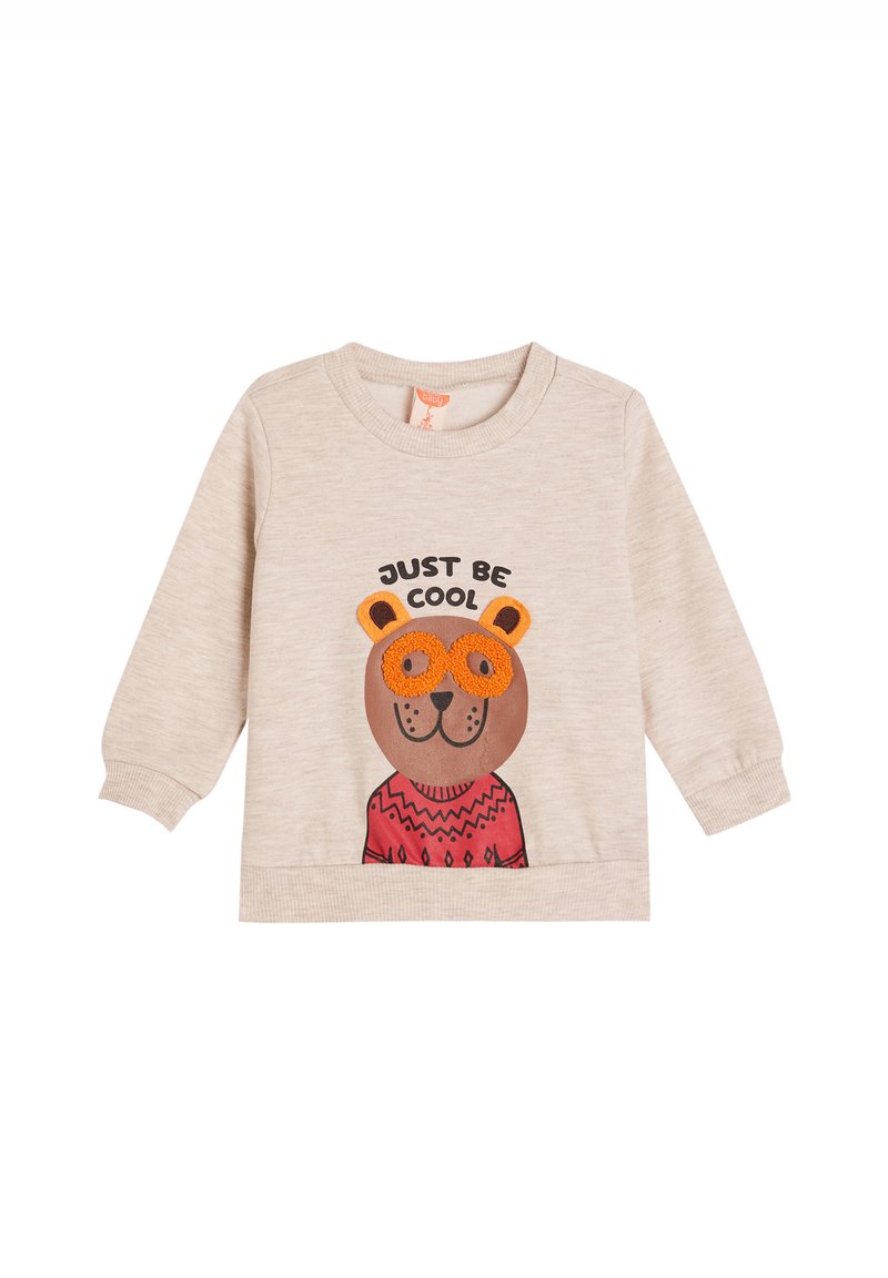 Sudadera beige clara de manga larga, con un oso de dibujos animados que lleva gafas naranjas y un suéter rojo con patrones. El texto dice "SOLO SE COOL".