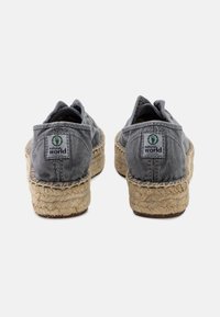 Szürke vászon espadrilles, jutaszoknyával, varrott varrással és egy kis logó címkével a hátsó részen. Kerek orrú dizájn és puha textúra.