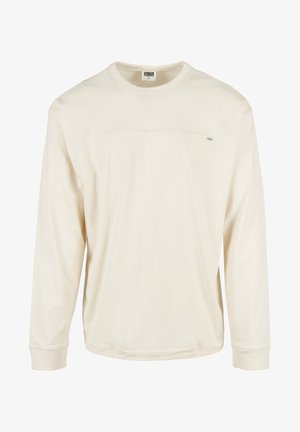 Jasno beżowa, długosleeve koszula wykonana z bawełny. Posiada okrągły dekolt, ściągacze na rękawach oraz subtelne logo na klatce piersiowej. Gładka faktura.