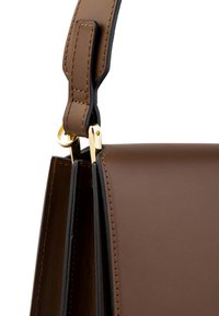 Borsa a tracolla in pelle marrone con accessori in metallo dorato, caratterizzata da cuciture visibili e una texture liscia, che mette in mostra un design strutturato.