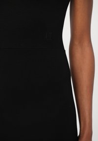 Black fitted dress featuring a smooth texture, a simple design, and an embroidered "AX" logo on the left waist.