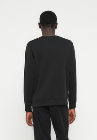 Μαύρο φούτερ με στρογγυλή λαιμόκοψη κατασκευασμένο από βαμβακερό μείγμα υφάσματος, με άνετη εφαρμογή, ριμπ μανσέτες και τελείωμα. Χωρίς ορατά σχέδια ή γραφικά.