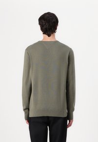 Pulover cu mânecă lungă, de culoare verde măslin, cu un model subtil, guler și mansete ribbate și o margine dreaptă la spate.