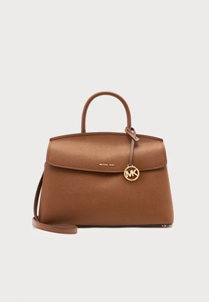 Sac à main en cuir marron Michael Kors avec poignée dessus, fermeture à rabat et breloque logo MK dorée sur un fond clair uni.