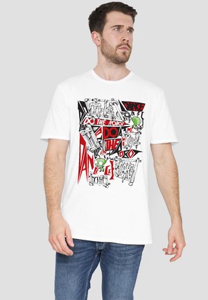 White cotton t-shirt featuring bold graphic print with red and black text and illustrations, including a green character, on the front.
