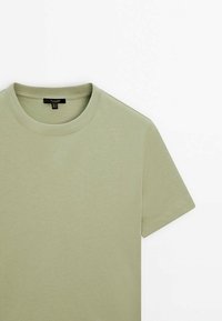 Oliwkowy bawełniany t-shirt z okrągłym dekoltem, krótkimi rękawami i miękką fakturą. Posiada metkę z informacjami o marce i rozmiarze.
