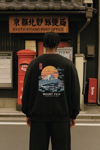 Άτομο που στέκεται έξω από το Ταχυδρομείο Κιότο Κιτάνο, φοράει μαύρο φούτερ με πολύχρωμο σχέδιο του Όρους Φούτζι και ηλιοβασίλεμα στην πλάτη.