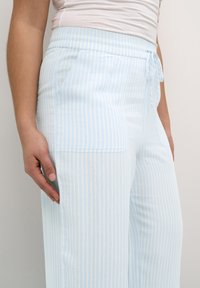 Pantalons à jambes larges rayés bleu clair en tissu doux ; dotés d'une taille élastique avec un nœud et de poches latérales.