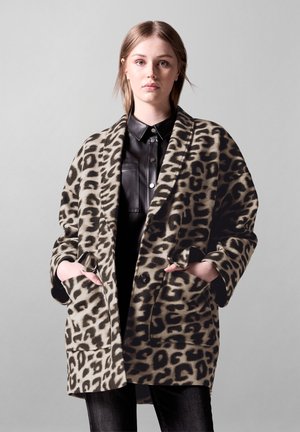 Leopard-print coat made of soft fabric, featuring an open front, wide sleeves, and two front pockets, layered over a black shirt.