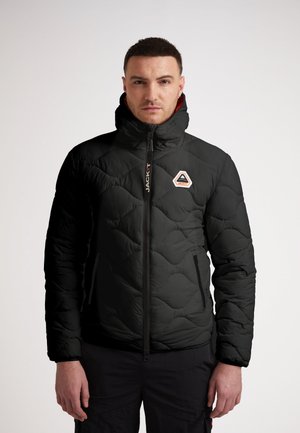 Sort puffjakke med høj krave, kviltet tekstur og sidelommer. Har et logo i en orange og hvid trekant på brystet.