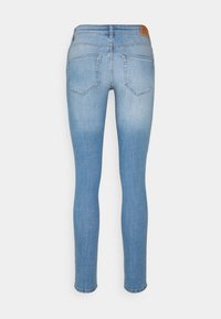 Jeans ajustados de mezclilla azul claro con un lavado desgastado, que cuentan con bolsillos traseros estándar y un parche de cuero marrón en la cintura.