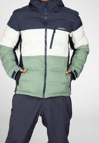 Padded jacket with a color-block design, featuring dark navy, white, and mint green sections. Zippered pockets and adjustable hood.