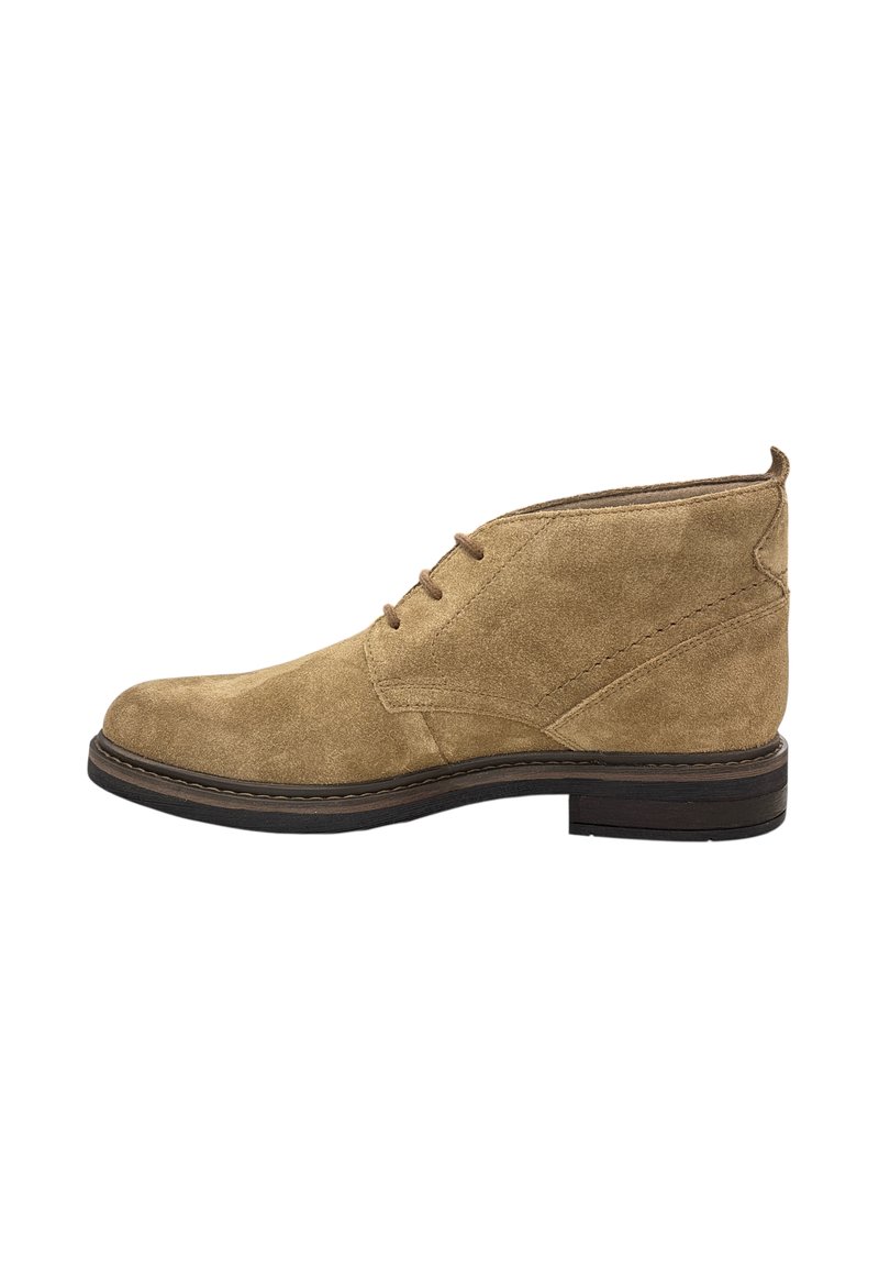 Stivaletto in suede beige con punta arrotondata, chiusura con lacci e suola in gomma marrone scuro a contrasto. Presenta sottili dettagli di cucitura.