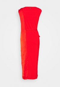 Robe rouge présentant un mélange de textures côtelées et lisses, avec une fente latérale et une silhouette cintrée. Ceinture ajustable pour un meilleur ajustement.