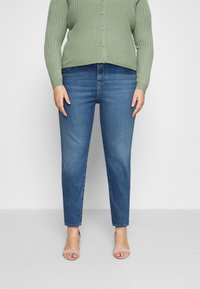 Vaaleanvihreä ribbikuvioinen neulejakku, jossa napit, yhdistetty tummansinisiin suoriin farkkuihin ja luonnonvärisiin remmikkäisiin korkokenkiin. Yksinkertainen ja rento asu.