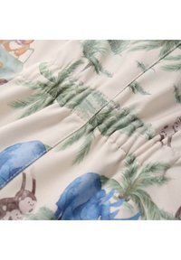 Tissu floral avec des formes bleues et des feuilles de palmier vertes, avec une texture froncée sur fond crème. Matériau léger et lisse.