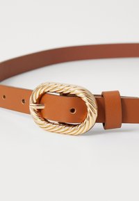 Bruine leren riem met een gedraaide gouden gesp. Beschikt over een gladde textuur en verschillende gaatjes voor aanpassing.