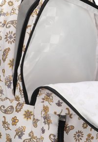 Rugzak met een bloemig paisleypatroon in geel, paars en blauw op witte stof. Voorzien van zwarte ritsen en een gladde binnenvoering.