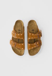 Καφέ σουέτ σανδάλια με δύο ρυθμιζόμενες ιμάντες, με διακοσμητικά καρφιά, και ανατομική σόλα από φελλό. Μέγεθος 38 αναγραφόμενο εσωτερικά.