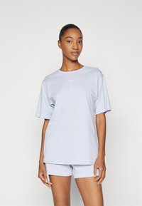 Light purple t-shirt with short sleeves and a round neckline, paired with matching shorts. Features subtle branding on both garments.