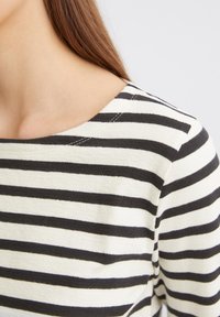 Gestreiftes Langarmshirt mit horizontalen schwarzen und weißen Streifen, weichem Textil und runder Ausschnitt.