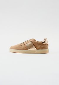 Beige semsket sko med metalliske detaljer, rund tå, flat gummisåle og snøredsdesign. Har strukturert panelering på sidene.