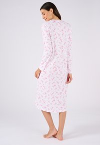 Vestito da notte a maniche lunghe in un leggero tessuto bianco, decorato con motivi floreali rosa. Presenta un collo rotondo e un design alla lunghezza del ginocchio.