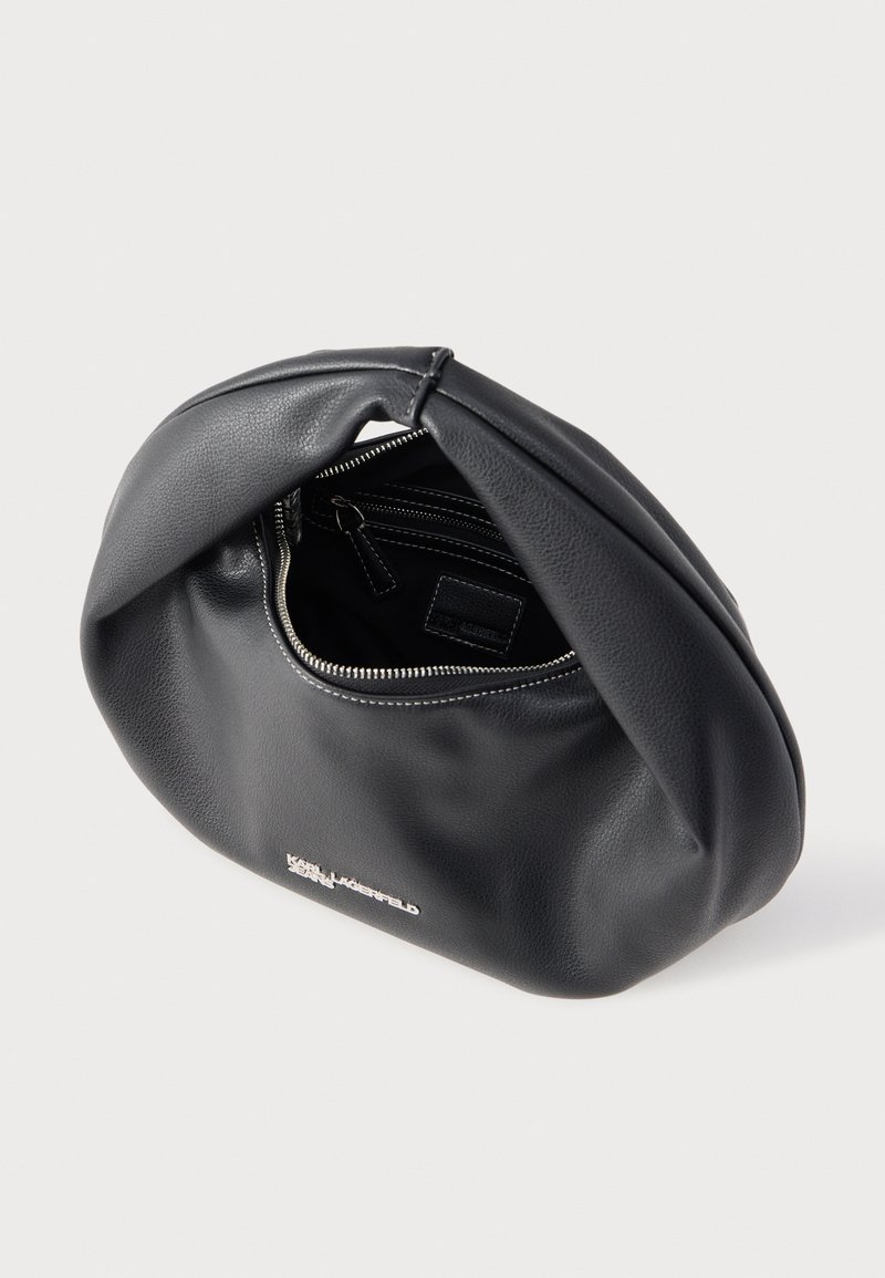 Bolso de cuero negro suave con cremallera plateada parcialmente abierta, bolsillo interior expuesto y pequeño logotipo metálico en el frente.
