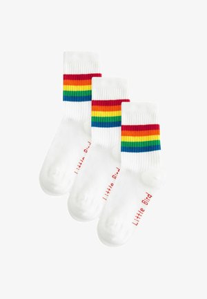 Three pairs of white cotton socks with a ribbed design, featuring rainbow stripes in red, orange, yellow, green, and blue. "Little Bird" printed in red.