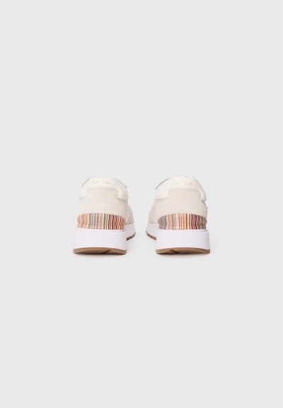 Adidași albi cu un superior texturat de crem, un accent multicolor în dungi pe toc și o talpă intermediară albă peste o talpă de cauciuc bej.