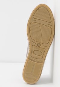 Semelle de chaussure en suède gris avec une base en caoutchouc texturé. Présente un design léger avec des rainures pour une meilleure adhérence et une étiquette indiquant "Fabriqué en Espagne".