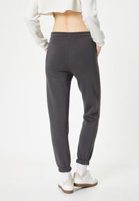 Grijze joggers van een katoenmix met een elastische tailleband, ribgebreide enkelmanchetten en zijzakken. Gecombineerd met witte sneakers en sokken.