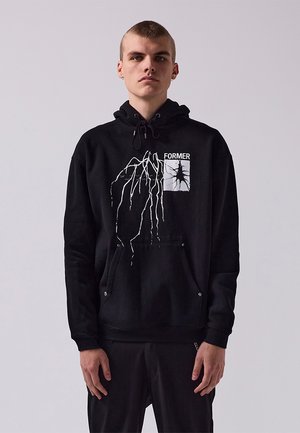 Black hoodie made of soft fabric featuring a drawstring hood, front pocket, and a white graphic design with the word "FORMER" and tree-like patterns.