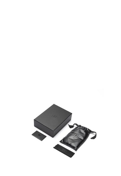 Černá obdélníková krabička s raženým logem, doplněná lesklým černým popruhem na stažení, plochou kartou a úzkým páskem.