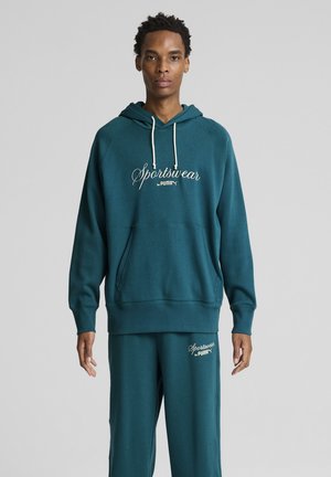 Teal hoodie with white drawstrings, featuring "Sportswear by PUMA" logo. Paired with matching sweatpants. Soft fabric, relaxed fit.