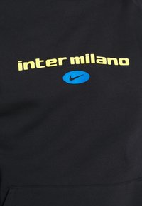 Tissu noir avec texte jaune « inter milano » au-dessus d'un ovale bleu contenant un logo Nike Swoosh noir, centré sur le matériau.