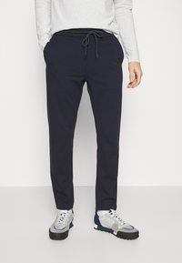Marineblauwe joggingsbroek met een elastische tailleband, koordsluiting en taps toelopende benen, gemaakt van zachte stof voor comfort.