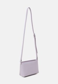 Liten lavendelfärgad crossbody-väska i slätt läder. Har en långjusterbar rem och en dragkedja upptill för stängning. Enkel rektangulär form.